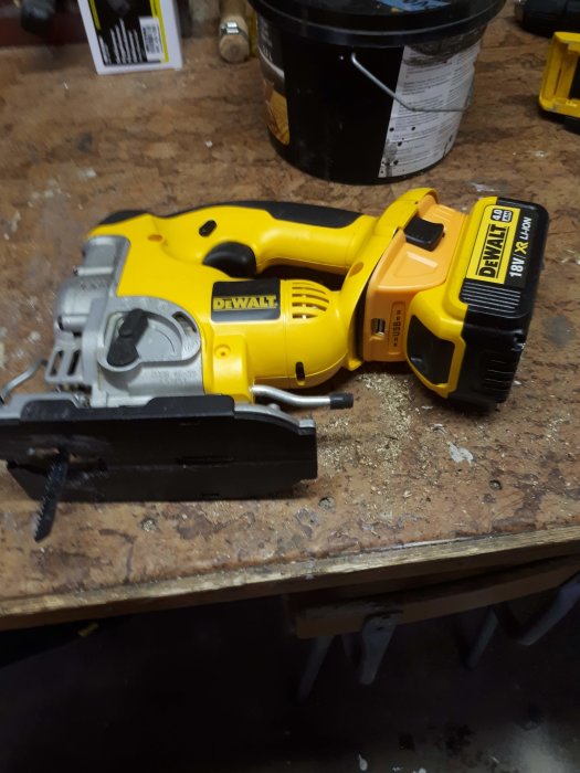 Äldre DeWalt 18V sticksåg uppdaterad med en ny adapter för XR-batterier och USB-port ligger på en arbetsbänk.