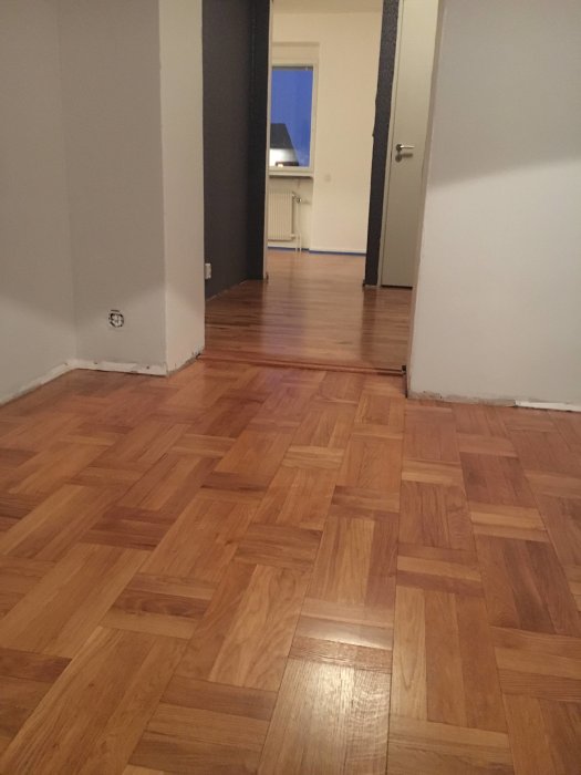 Nyinstallerat parkettgolv i en lägenhet med synlig övergång till äldre golv.