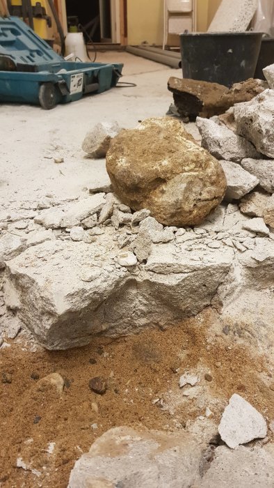 Ombyggnad i tvättstuga med uppbruten betong och stora stenblock på golvet.