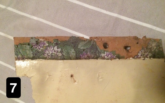 Fragment av historisk tapet med blommönster i kornblått och vitt på en grön bakgrund, troligen från ett äldre hem.