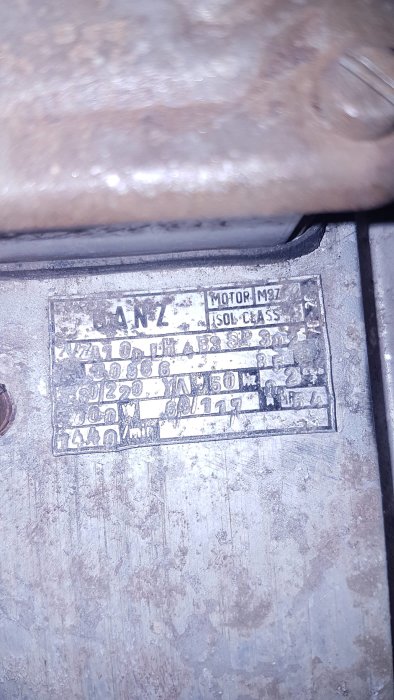 Närbild av ett slitet typskylt på en motor med olika tekniska specifikationer.
