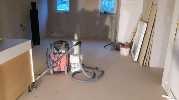 Nylagt spångolv i ett halvfärdigt hem under renovering med verktyg och material synligt.