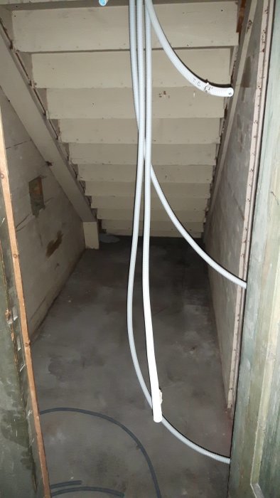Bild på en gammal pardörr framför utrymmet under en trappa med elinstallationer, avsett att bli förråd.