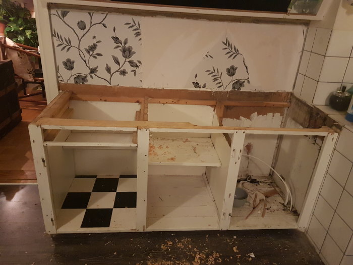 Dismantled kitchen cabinetry with removed countertops and visible plumbing, in preparation for renovation.