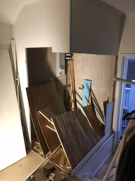 Upprivna delar av ett trägolv och skräp i en hög inne i ett rum under renovering.