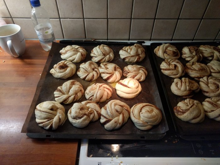 Nybakade kanelbullar på bakplåt i ett kök, redo för ugnen.