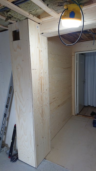 Pågående badrumsrenovering med oskyddad rörgenomföring och arbetslampa.