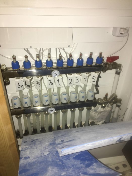 Värmefördelare för golvvärme med numrerade ventiler och mätur.