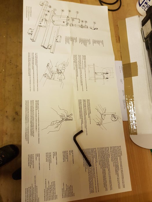 Instruktionsblad för kopieraggregat till träsvarv med ritningar och text, samt en hexnyckel ovanpå.