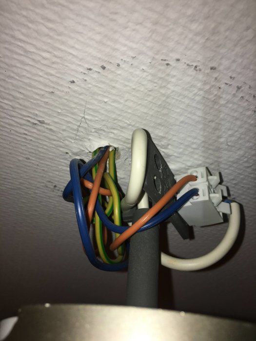 Elektriska kablar och rör synliga utan dosa i taket vid installation av vägguttag.