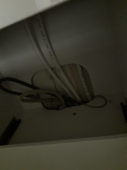 Uttag i bakkant på ett IKEA-skåp med synliga ledningar och hål för installation.