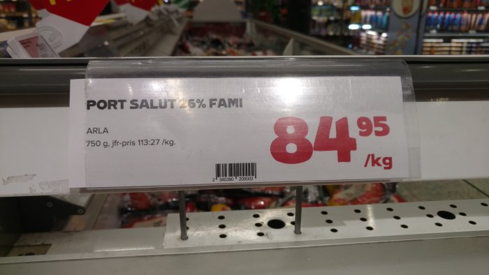 Prisskylt på Coop för Port Salut ost med pris och jämförpris per kilogram.