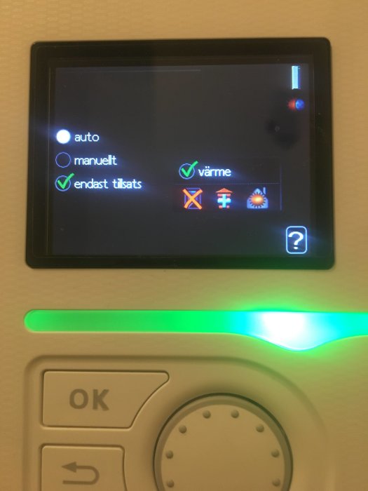 Digital termostat med inställningar för värme, grönt ljus indikerar aktivt läge.