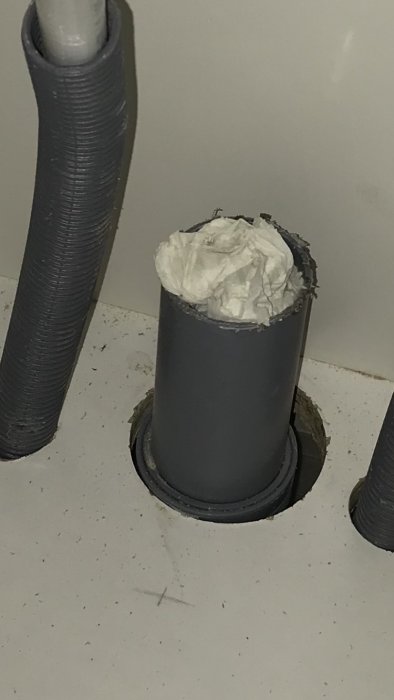 Nya avloppsrör i kök med rörböj, täckt av torkad pappershandduk, nära golvet.