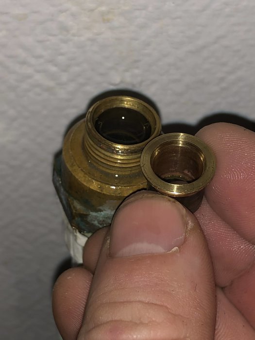 Närbild på en hand som håller två kopparledningsändar bredvid en gängad anslutning.