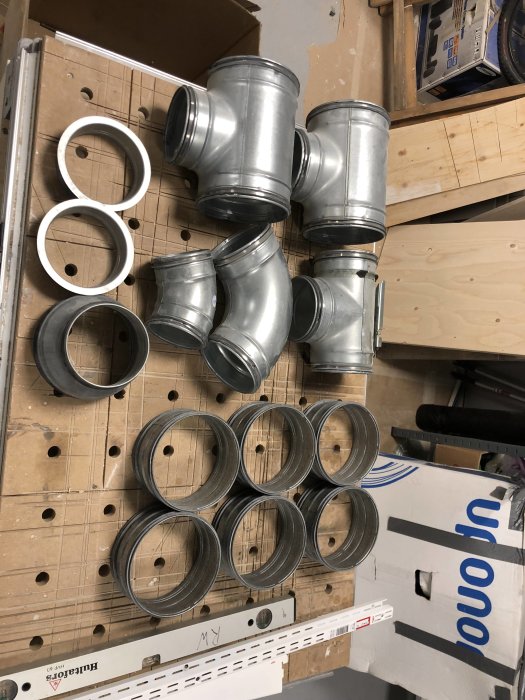 Ventilationsdelar inklusive T-stycken och nippel i galvaniserat stål, plus trumstosar och bockade rör.