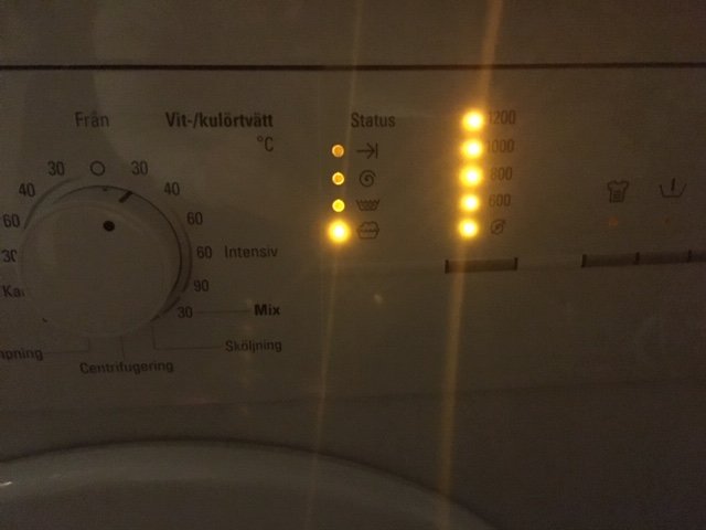 Tvättmaskinens kontrollpanel med blinkande varvtalslampor och en tvättlampa tänd.