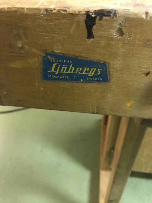 Närbild på en trähyvelbänk med en Sjöbergs logotyp, tecken på slitage och saknad trälist.