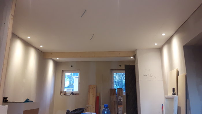 Renoverat rum med nyinstallerade, inbyggda spotlights i taket och byggmaterial på golvet.