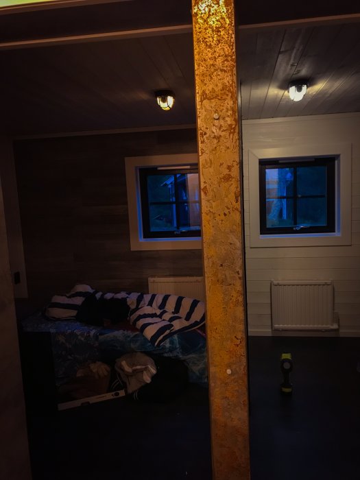 Nyinstallerad takplåt i ett rum med träpanel och två fönster, verktyg syns på golvet.
