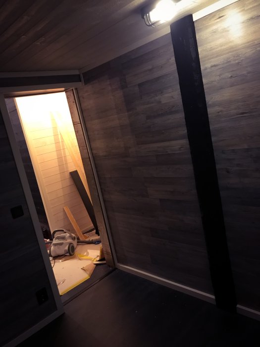 Nyligen färdigställt gästrum med träpanel på väggarna och byggmaterial på golvet.