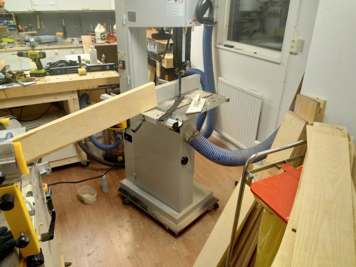 Träplankor framför bordssåg i verkstad under förberedelse för att skapa skåp.