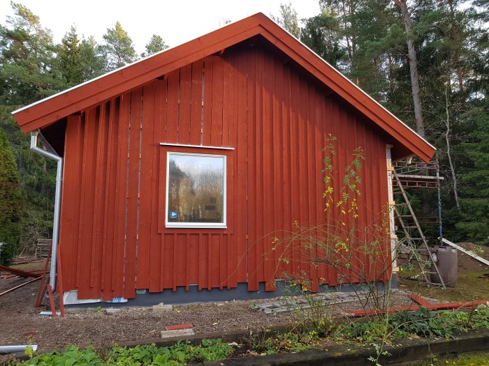 Rödfärgad husgavel efter borttagen byggställning med monterade överbleck och fönsterfoder.