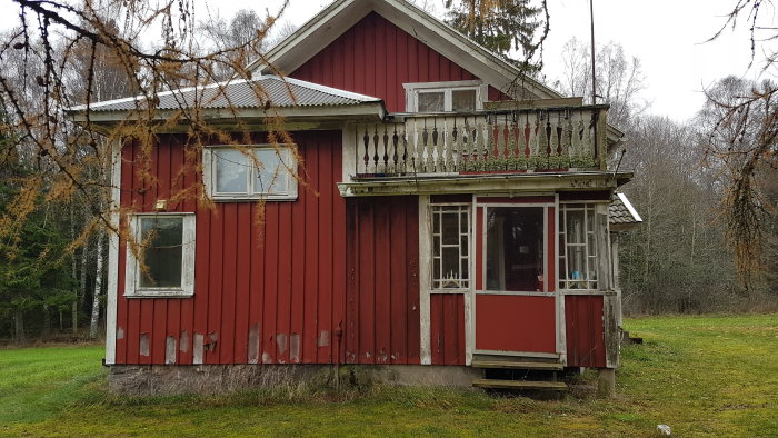 Rött hus med vit veranda och nedsliten trappa, potentiell rivningsdel för tillbyggnad.