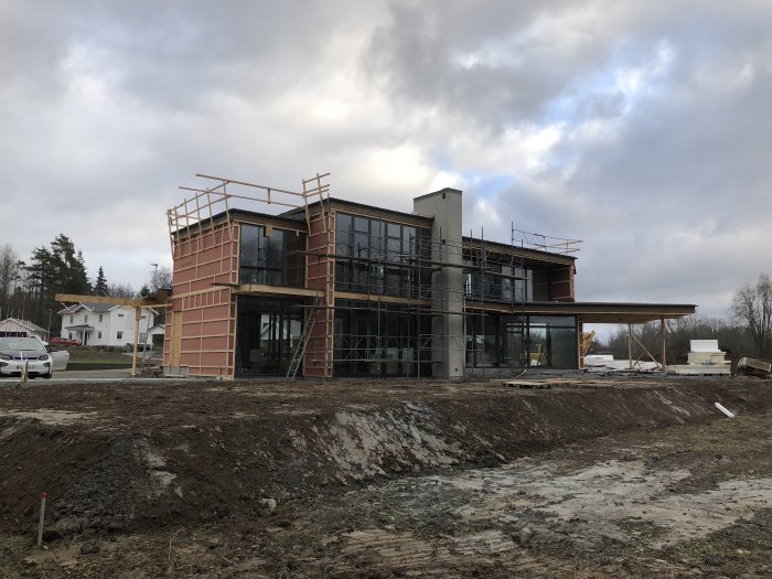 Halvfärdigt hus med plåttak till 50%, isolering och stomme för carport synlig.