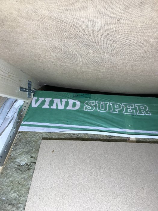Detaljvy av en vindavledares installationsområde med synlig luftspaltsboard och häftad vindduk märkt 'VIND SUPER'.