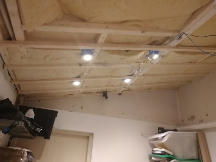 Delvis renoverat tak med isolering och inbyggda spotlights, oavslutade elinstallationer synliga.