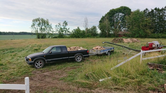 Chevrolet S10 pickup med släpkärra lastad med byggavfall på en gräsmark.