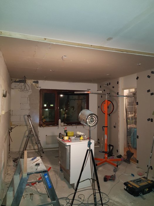 Renoveringsprocess av ett kök med ommålade väggar och borttaget kakel, arbetsmaterial och verktyg synliga.