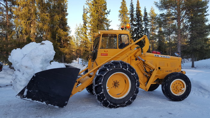 Gul BM Volvo LM 218 lastmaskin från 1965 i ett snöigt landskap med lyft skopa och en stor snöhög.