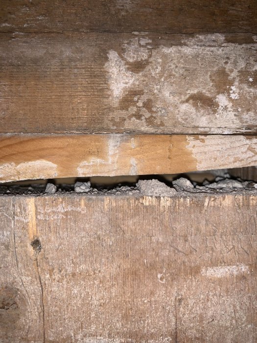 Vanha, kulunut puulattia, jossa näkyy halkeama ja roskia rakenteessa.