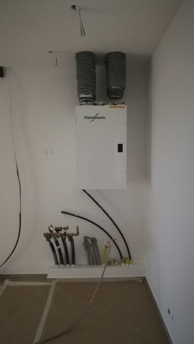 Installerad FTX-ventilationsenhet från FläktWoods med upphängda ventilationsrör i taket.