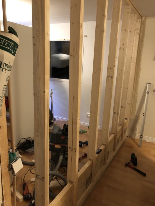 Stomme av träreglar med urtag under renovering inomhus, verktyg och byggmaterial på golvet.