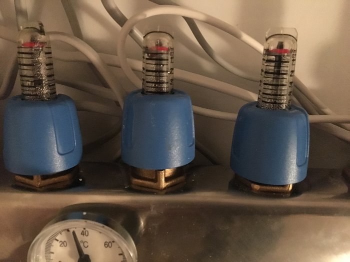 Tre växelventiler med blåa huvuden och inställningsskala överst, bredvid en termometer som visar 37 grader.
