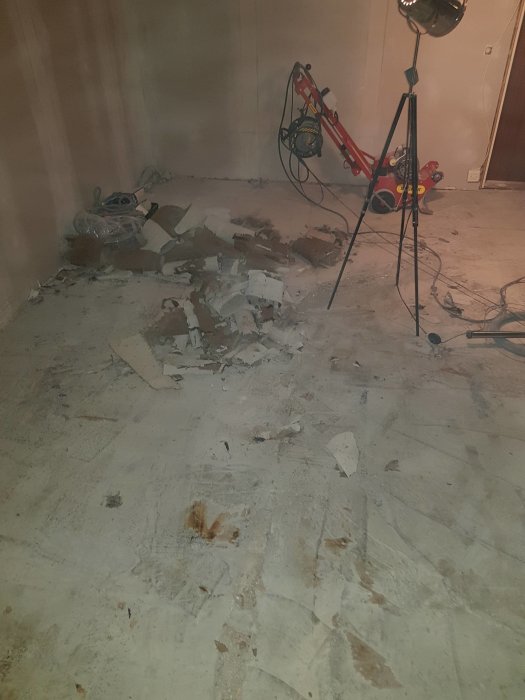 Rum under renovering med röra av borttaget material på golvet och verktyg i bakgrunden.