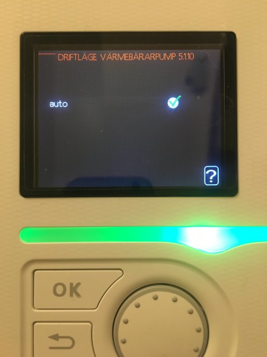 Digital termostat för värmepump i autosläge med grönt statusljus.