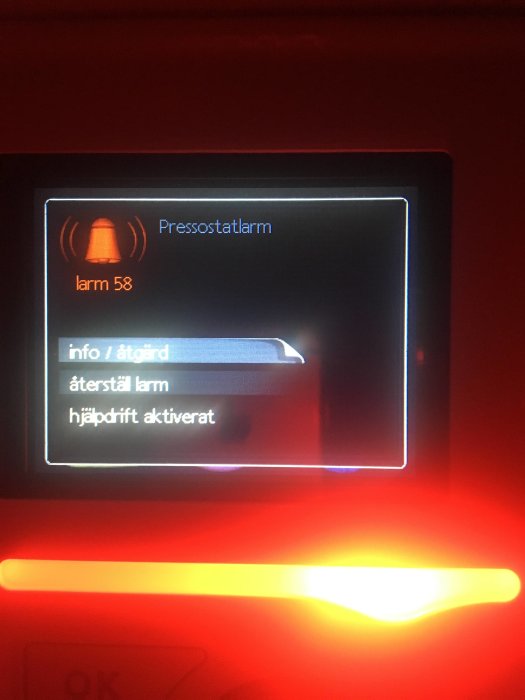 Röd larmdisplay med texten "Pressostatalarm" och alternativen "återställ larm" samt "hjälpdiff aktiverat".