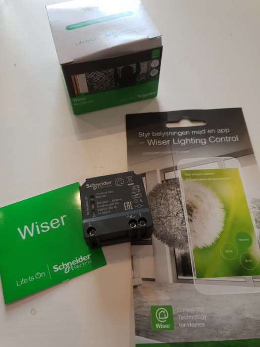 Wiser mikromodul från Schneider Electric med förpackning och produktinformation på bord.