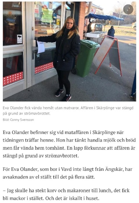 Kvinna står utanför en stängd matbutik med en lapp om strömavbrott i fönstret.