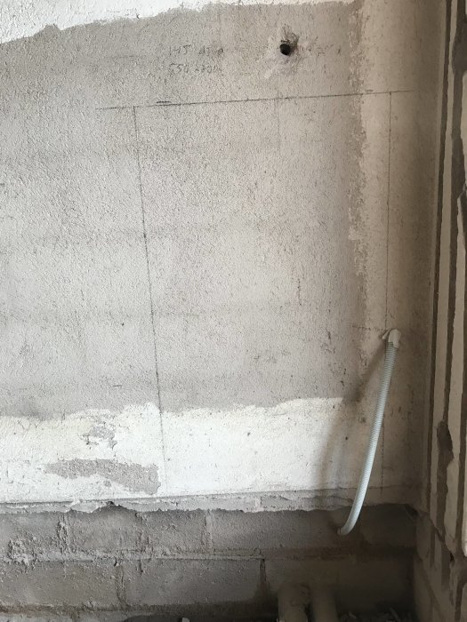 En oputsad vägg med markerat område för fördelarskåp och framstickande elkabel.