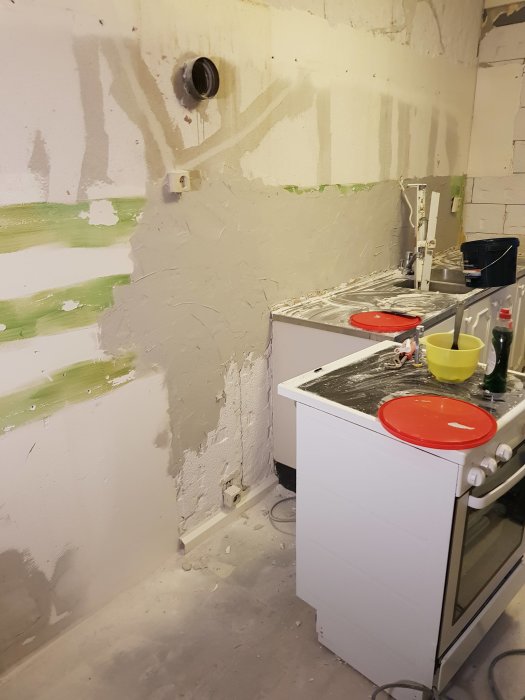 Eluttag bakom spis i ett omålatt kök under renovering.
