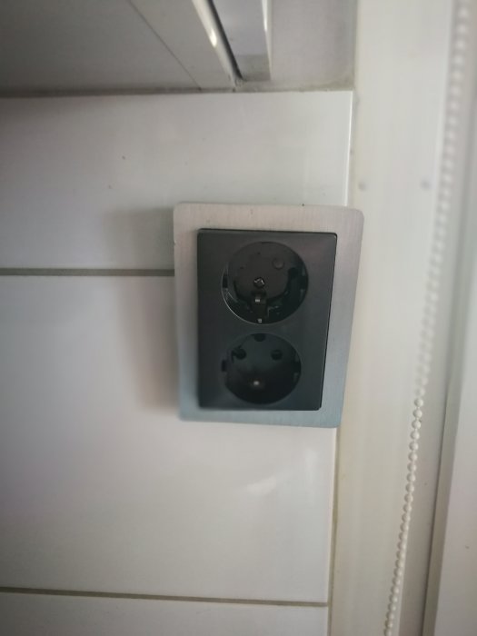 Söndrat vägguttag i köket med synlig skada på den ena kontakten.