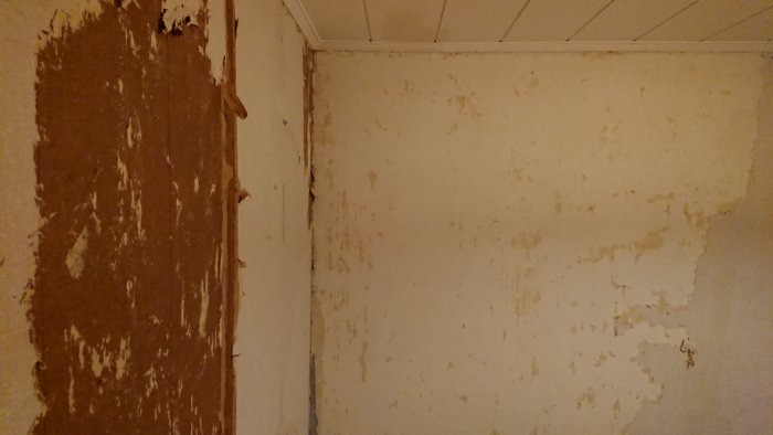 En hörnvy av ett rum med en brun träskiva och en betongvägg med vitt material på sig.