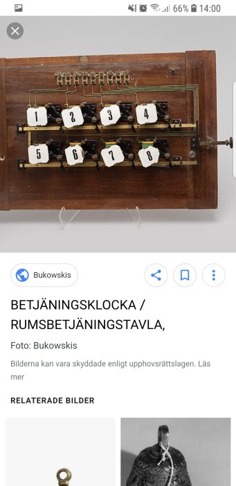 Gammal betjäningsklocka / rumsbetjäningstavla med numrerade knappar på träbräda.