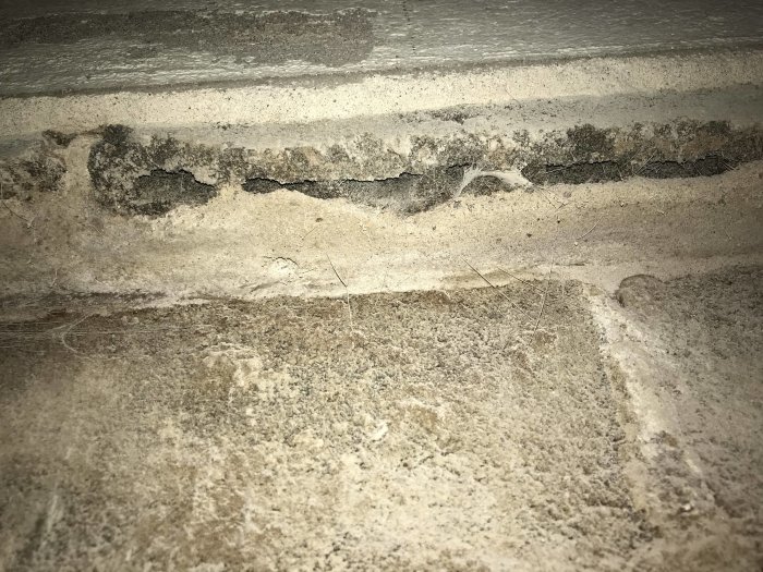 Vy underifrån på en betongkant med en ojämn påbyggnad och damm.