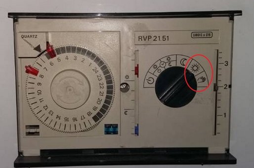 Äldre fjärrvärmepump från Landis och Gyr med inställningsratt markerad med symboler för sol och hand.